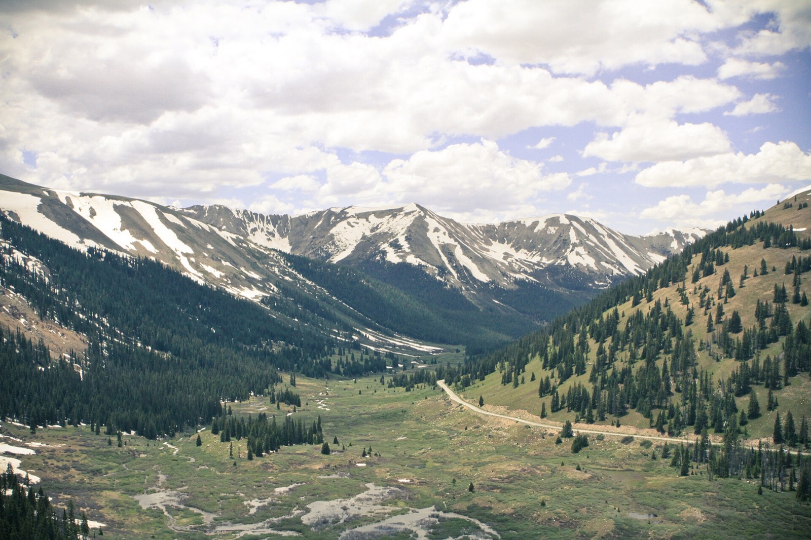 The view from Independence Pass on the Continental Divide in July, with snowfields still lying on the peaks above a green valley